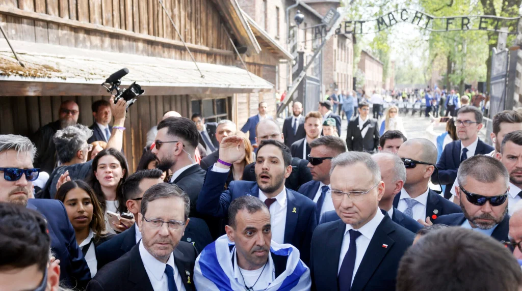 Poland’s President Andrzej Duda, at right, and Israel’s President Isaac Herzog flank Eli Sharabi, who was held hostage in Gaza for 491 days after Hamas murdered his family on Oct. 7, 2023, during the March of the Living in Auschwitz, April 24, 2025. (Wojtek Radwanski/AFP via Getty Images)